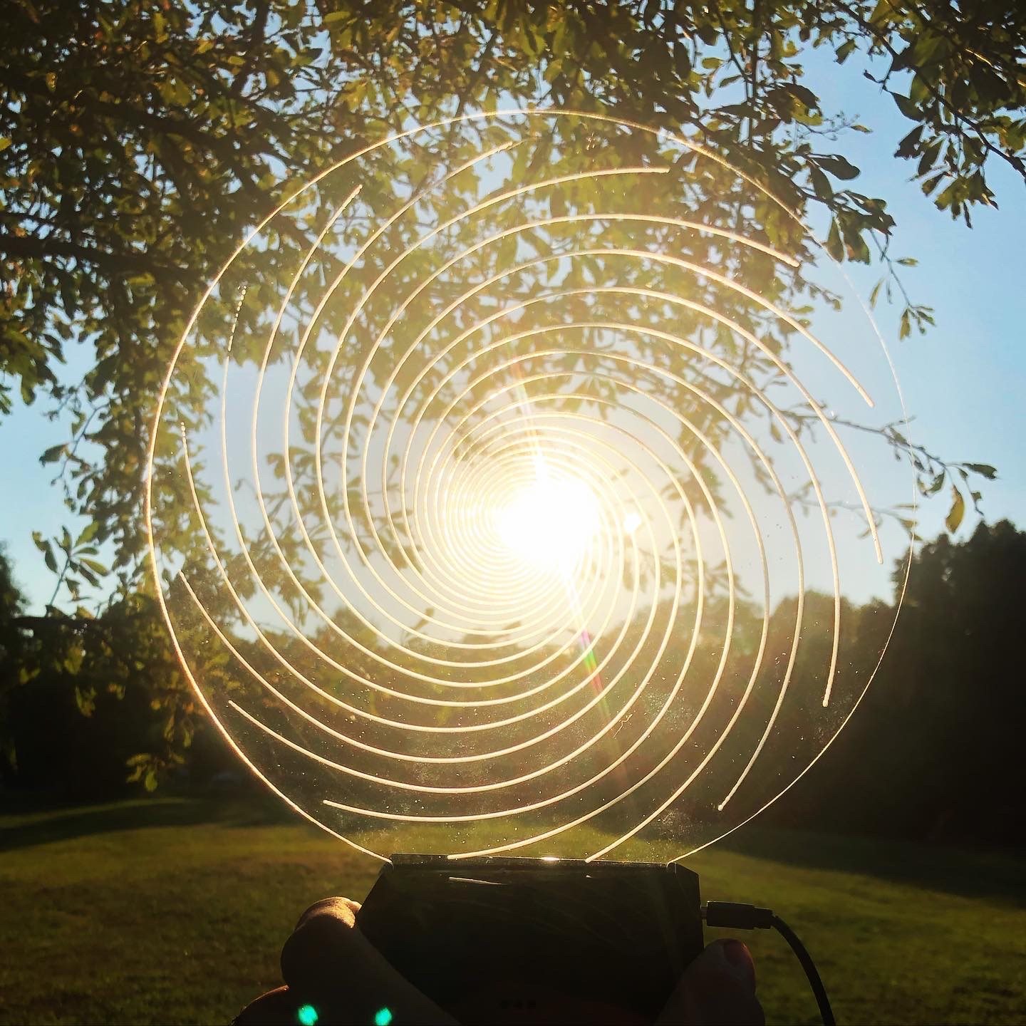 Illuminated acrylic spiral held against the setting sun