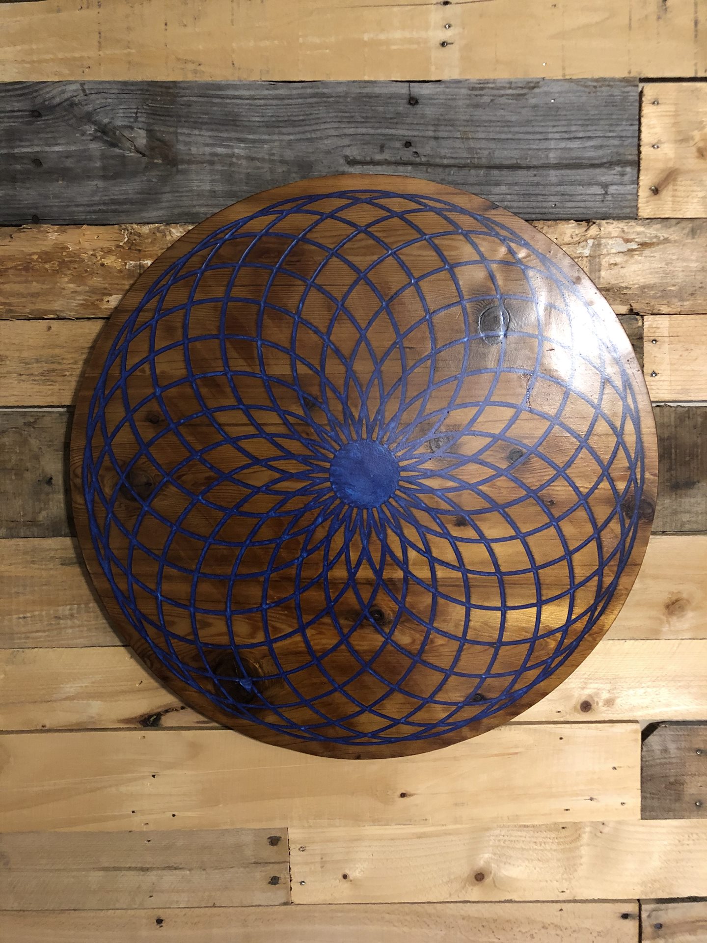 Blue interlaced torus pattern in a circular wood panel