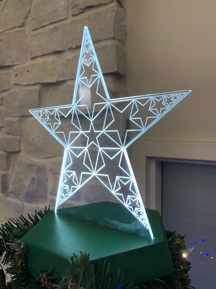 Illuminated recursive acrylic star mounted on a green base