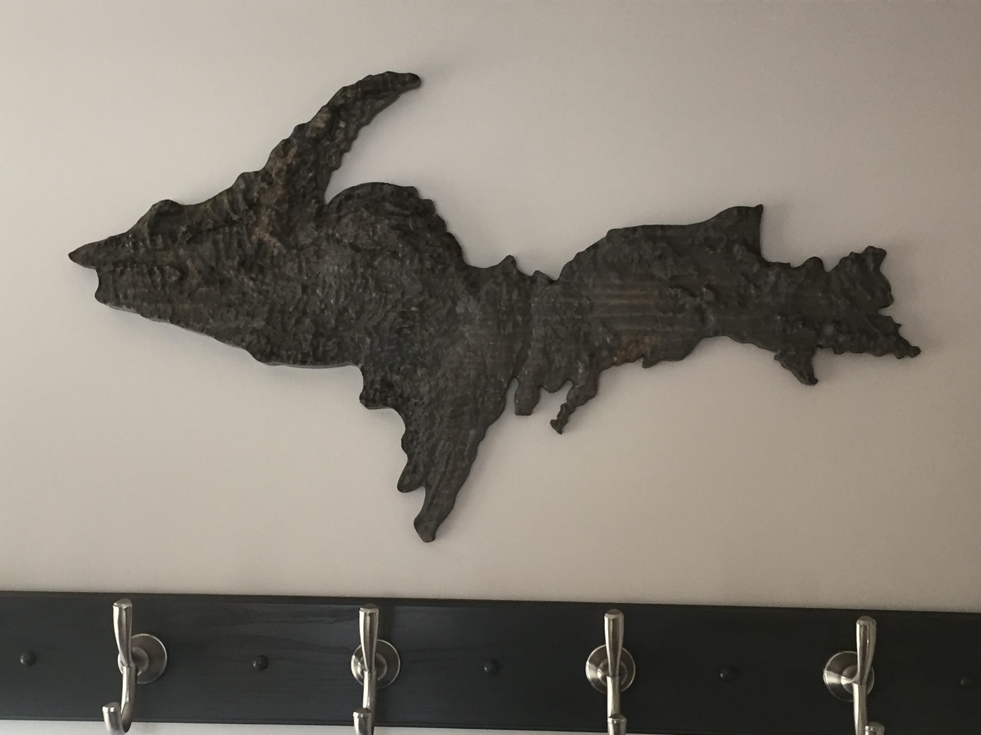 Textured metal silhouette of Michigan’s Upper Peninsula mounted above a coat rack